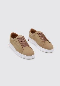 zapatillas de ante beige con cordones marrones, punta redonda, suela de goma blanca, diseño minimalista, textura suave y detalle de costura lateral.