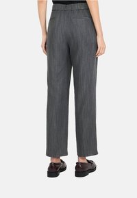 Pantaloni largi grigi con un tessuto testurizzato, dotati di una vita alta elastica e due tasche posteriori, abbinati a scarpe scure.