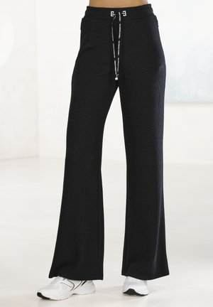 Black flared sweatpants made of textured fabric, featuring a drawstring waist with silver hardware and minimalistic design.