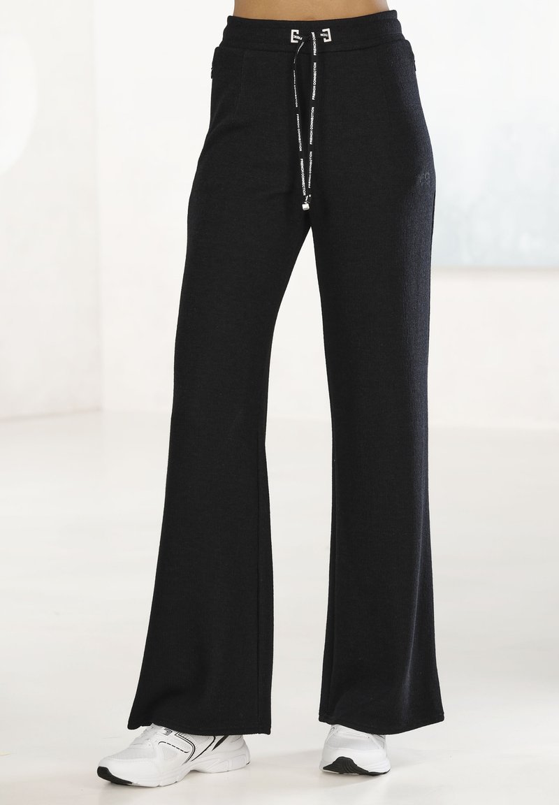 Schwarze, ausgestellte Sweatpants aus strukturiertem Material, mit einem Kordelzugbund und silbernen Details sowie einem minimalistischem Design.