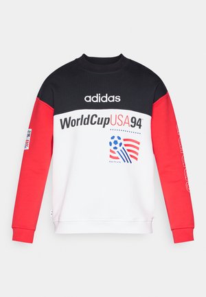 Adidas sweatshirt met een zwarte top, een wit lijfje en rode mouwen. Voorzien van World Cup USA 94-graphics en een geribde hals. Gemaakt van zacht materiaal.
