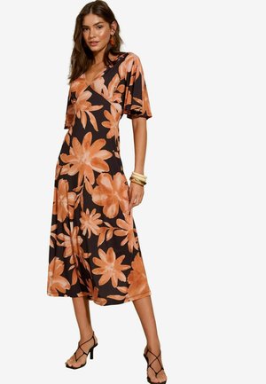Robe floral avec un fond noir, ornée de grandes fleurs orange. Design en V, manches courtes et coupe fluide à mi-hauteur.