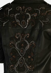 Giacca di pelle nera con intricati motivi ricamati in fili grigi, bronzo e argento sul retro, che creano un design testurizzato.