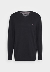 Pull à col en V gris foncé en matière douce, avec manches longues et un petit logo avec des détails rouges et blancs sur la poitrine.