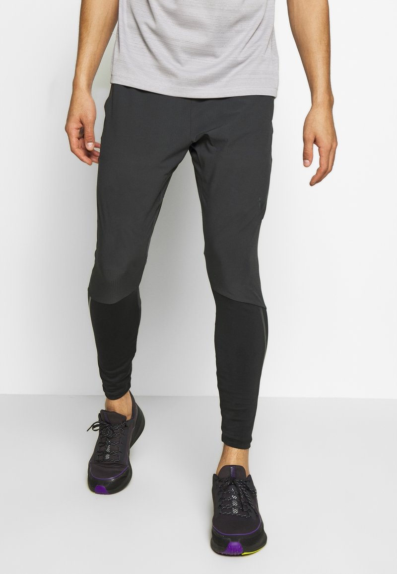 Leggings deportivos negros con diseño ajustado, tela texturizada y acentos en bloques de color. Combinados con zapatillas negras con detalles morados.