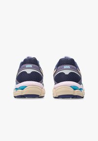 Un paio di scarpe da corsa blu navy e beige con tomaia in rete e ammortizzazione in gel, viste da dietro su uno sfondo bianco.