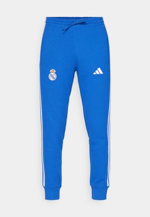 Blue sweatpants made of cotton blend with white side stripes, elastic waistband, and drawstring. Features Real Madrid logo on left thigh.