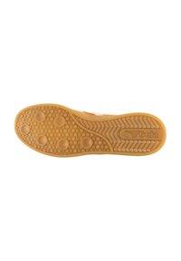 Semelle de sneaker en caoutchouc brun clair, présentant une surface texturée avec des rainures circulaires et horizontales, marquée "Gola."