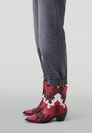 Bottines en cuir rouge et bourgogne avec des découpes complexes et des accents cloutés, dotées d'un bout pointu et d'un talon block.