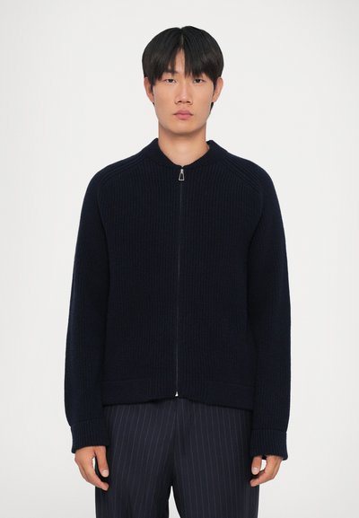 Cardigan a maglia blu navy con zip frontale, texture a costine e maniche raglan. Dotato di colletto alto, si estende fino ai fianchi.
