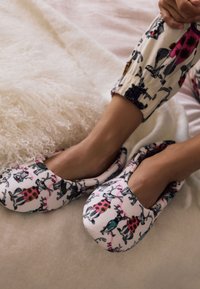 Pehmed mustrilise kangaga valged sussid värvikate loomapiltidega, ümarate servadega ja paindlike avadega mugavaks kandmiseks.