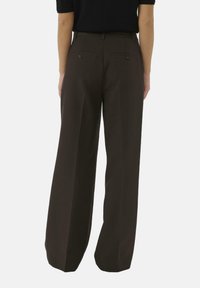 Bruine wijde broek met een gladde textuur, achterzakken en een getailleerd figuur bij de taille. Het materiaal lijkt lichtgewicht en gestructureerd.