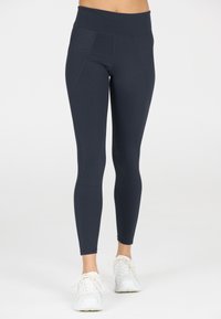 Marinblå hög midja leggings i stretchmaterial med sömmar och en mjuk textur. Kombination med vita träningsskor.