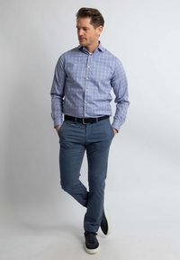 Lichtblauw geruite overhemd met knoopsluiting, gecombineerd met marineblauwe broek en zwarte sneakers. Soepele stof en slim fit.