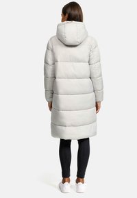 Light gray puffer coat with a hood, featuring horizontal stitching, long sleeves, and a mid-length design. Worn with black leggings and white sneakers.
