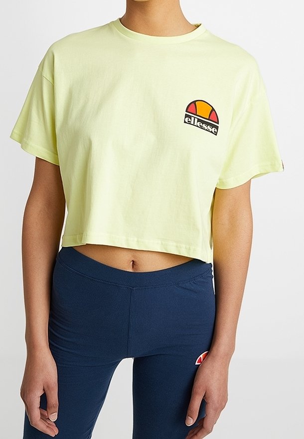 Zkrácený, krátký rukáv tričko z lehkého žlutého bavlněného materiálu. Obsahuje kulatý vícolor logo na levé části hrudi a má volný střih.