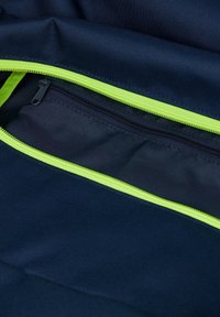 Navyfarbene Stofftasche mit leuchtend grünem Reißverschluss; enthält eine innere Reißverschlusstasche und weist eine glatte, strukturierte Oberfläche auf.