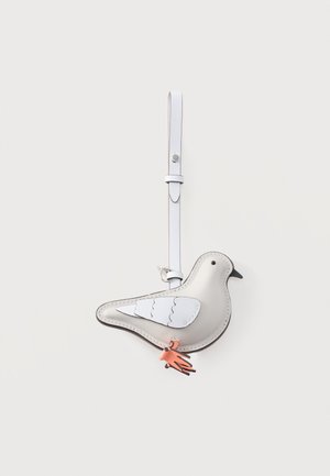 Λευκό δερμάτινο μπρελόκ σε σχήμα πουλιού με μαύρο ράμφος, λεπτομέρειες φτερών και ροζ φούντα που κρέμεται από λευκό λουρί.