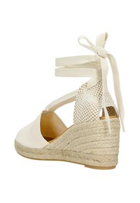 Beige espadrilové sandály na klínu s tkaninovým svrškem, vázáním kolem kotníků a juteovým obložením na podpatku. Hladký povrch, otevřené strany a kulatá špička.