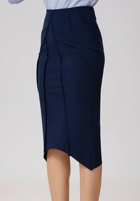 Jupe crayon marine à taille haute, présentant des détails de coutures verticales et un ourlet arrondi. Fabriquée en tissu extensible et lisse pour une silhouette ajustée.