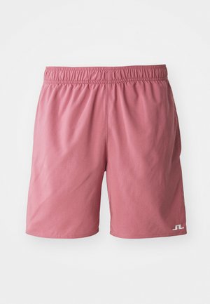 Pink swim shorts with an elastic waistband, smooth texture, and a small white logo on the lower left leg.