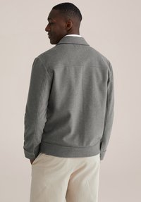 Szara kurtka z mieszanki wełny, z kołnierzem, bocznymi kieszeniami i zapinanymi na guziki mankietami. Gładka faktura z dopasowanym fasonem, pokazana od tyłu.