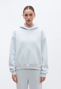 Camisola com capuz azul claro oversized feita de uma mistura macia de algodão, com bolso frontal, capuz com cordão e punhos canelados.