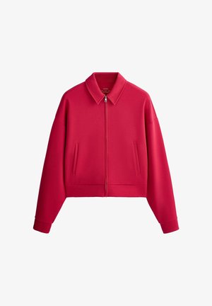 Červená bunda na zips so špicatým golierom, dlhé rukávy, dve bočné vrecká a rebrované manžety, zobrazená na bielom pozadí.