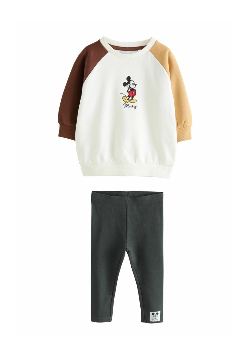 Setti, joka sisältää kermaisen yläosan ruskeilla ja vaaleanruskeilla raglan-hiisilla, jossa on koristeltu Mickey Mouse -grafiikka, ja tummanvihreät leggingsit.