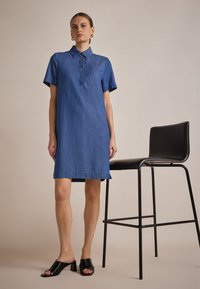 Denim-paitakleid mit Kragen, kurzen Ärmeln und Knopfdetails an der Vorderseite. Hat eine gerade Form und einen knielangen Saum.
