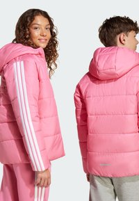 Rosa Pufferjacke mit Kapuze, ausgestattet mit weißen Streifenakzenten an den Ärmeln, gestepptem Muster und einem reflektierenden Detail auf dem Rücken.