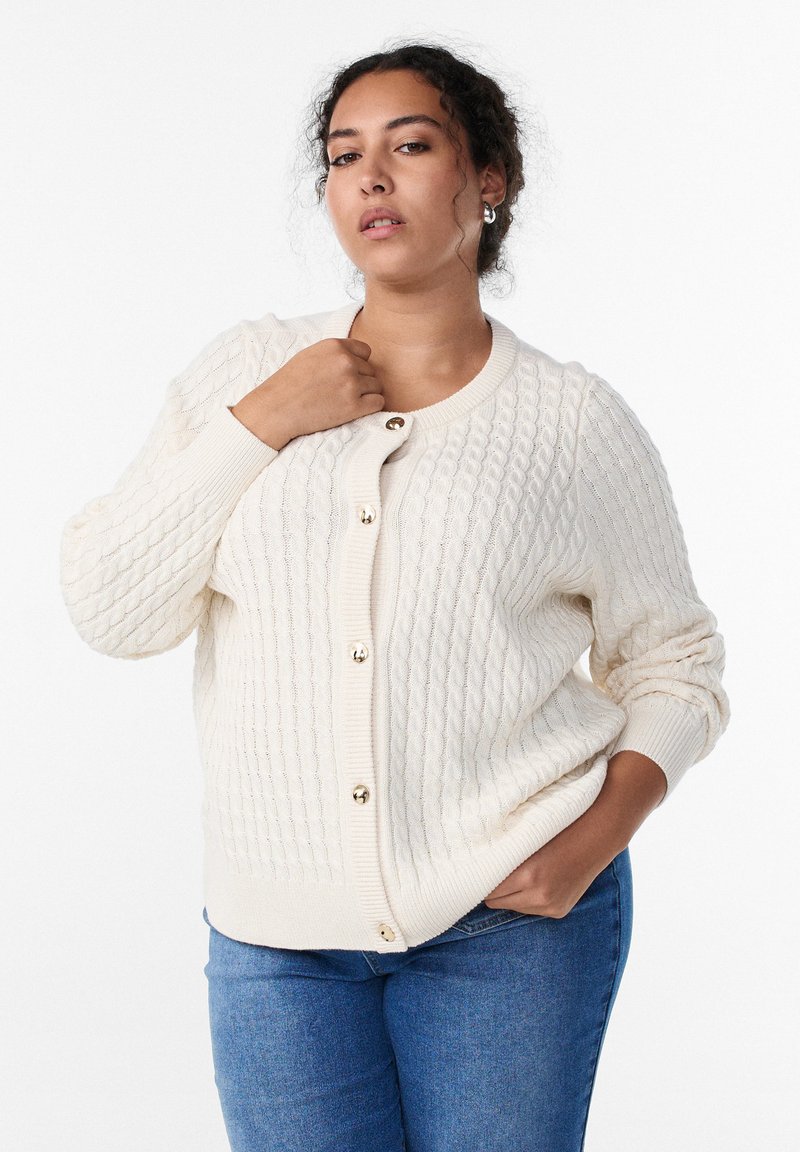 Kreemivärviline heegeldatud kardigan tekstuurse palmikmustriga, millel on ümmargune kaelus ja esiküljel kuldsed nööbid.