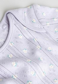 Lyslilla strikstof med små hvide og blågrønne blomster og strukturerede horisontale øjletstriber.