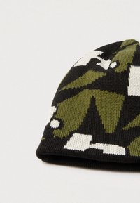 Gorro de punto con un patrón de camuflaje en verde oscuro, negro y blanco. Textura suave con borde enrollado y forma ajustada.