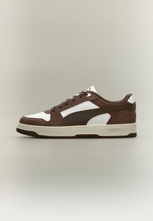 Καφέ και λευκό Puma χαμηλό sneaker με κορδόνια μπροστά και επώνυμη σόλα σε ουδέτερο φόντο.
