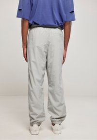 Lysegrå bukser med elastisk talje og smalle ankler, lavet af et letvægtsstof. Designet med en baglomme og minimalistisk stil.