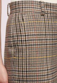 Tweedkjol med ett rutmönster i beige, svart och accenter av gult och rött. Har hög midja och sidofickor.