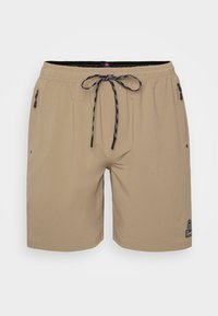 Shorts de bain beige avec une taille à cordon de serrage, des poches zippées sur les côtés et un petit logo près de l'ourlet. Fabriqués en tissu léger.
