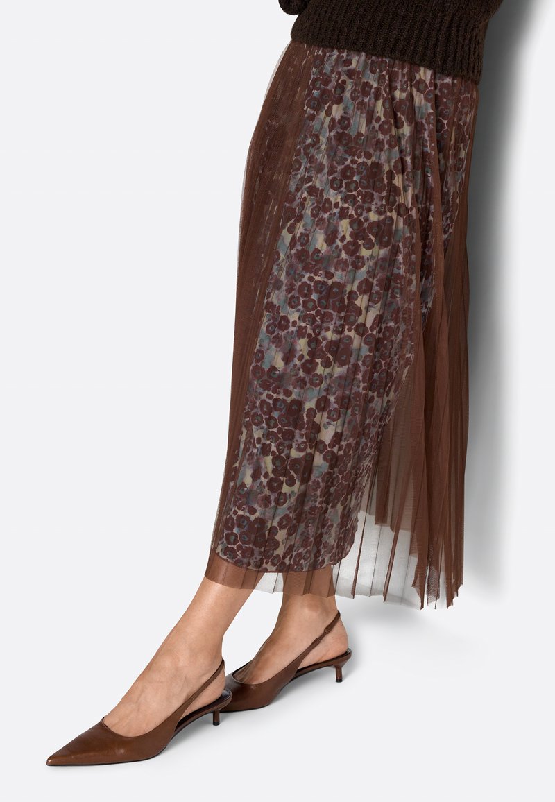 Brown sheer pleated skirt with floral pattern worn with dark brown pointed slingback low heel shoes.