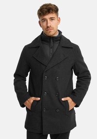 Schwarzer Woll-Peacoat mit doppelter Knopfleiste, großen Revers und zwei Taschen vorne. Verfügt über eine mit Reißverschluss versehenen inneren Schicht für zusätzliche Wärme.