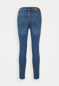 Narrow jeans i mörkblå denim, med en medelhög midja, två bakfickor och ett brunt läderpatch vid midjan. Slät textur.
