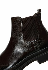 Stivale alla caviglia in pelle marrone con un pannello elastico testurizzato, design elegante, punta arrotondata e una robusta suola in gomma nera.