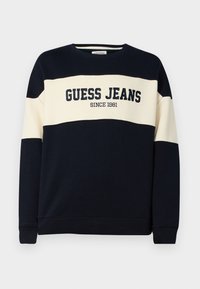 Marineblauwe sweatshirt met een beige horizontale stip, voorzien van de tekst "GUESS JEANS" en het detail "SINCE 1981". Gemaakt van zacht katoen.