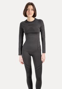 Sort atletisk langærmet top og leggings, tæt pasform med struktureret stof, med subtil branding og geometriske mønstre.