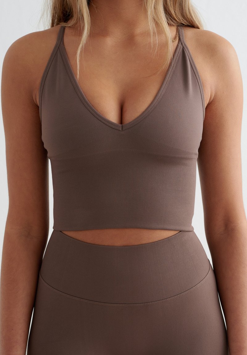 Bruine geribbelde crop top met een diepe V-hals en smalle bandjes, met een uitsnijding in de taille voor een aansluitende pasvorm. Soepele textuur.