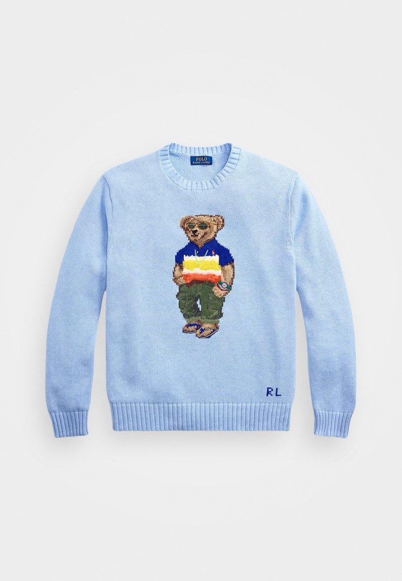 Šviesiai mėlynas megztinis, papuoštas siuvinėjimu, kuriame pavaizduotas lokys su akinių nuo saulės, apsirengęs mėlyna marškinėliais ir žaliais džinsais, su gumbinėmis rankovėmis ir apačia.