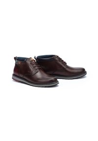Brown leather ankle boots with lace-up design, rubber sole, contrasting stitching, and padded collar. Smooth texture with subtle accents.