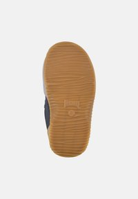 Suola di scarpa in gomma con texture rigata, di colore marrone e con un logo. Il materiale superiore sembra essere mescolato con tonalità blu navy e grigie.