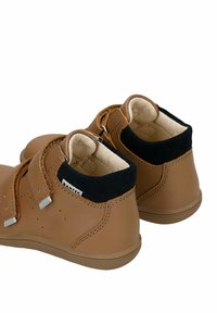 Brązowe skórzane buty dziecięce z czarnymi zamszowymi akcentami, dwoma paskami na rzepy i teksturowaną gumową podeszwą. Z boku posiadają perforacje.