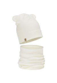 White ribbed knit beanie with bear ears and matching neck gaiter. Features a small, brown fabric label with a heart emblem. Soft texture.